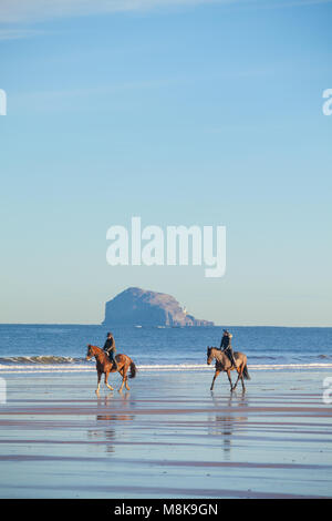 Zwei Reiter reiten ihre Pferde am Strand von North Berwick Schottland. Stockfoto