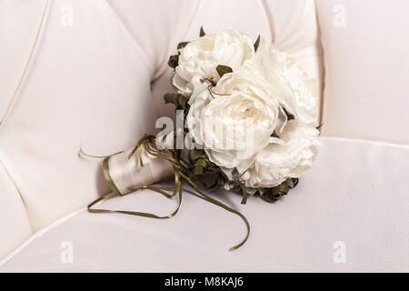 Brautstrauß aus weißen Rose in hellen Farben auf weißem Leder Stuhl Hintergrund Stockfoto