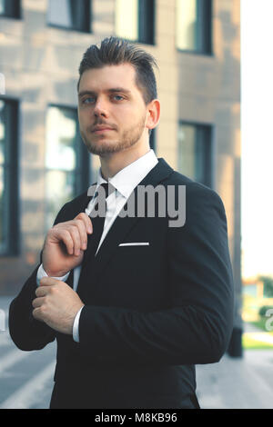 Geschäftsmann seine Krawatte einstellen am Eingang des Bürogebäudes Stockfoto