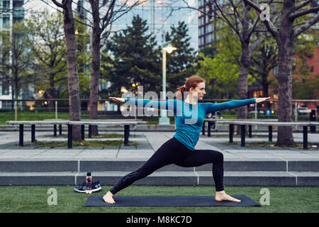 Kaukasische Frau übernimmt die Yoga in einem öffentlichen Park in New York City Stockfoto