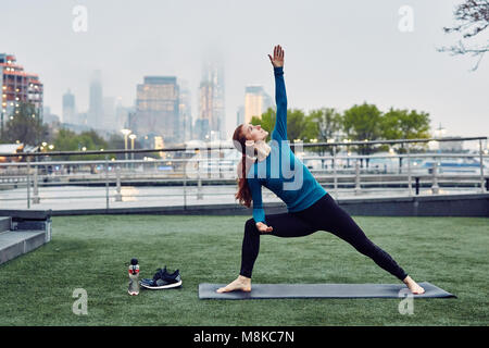 Kaukasische Frau übernimmt die Yoga in einem öffentlichen Park in New York City Stockfoto