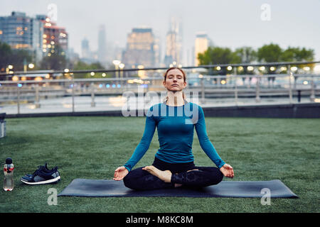 Kaukasische Frau übernimmt die Yoga in einem öffentlichen Park in New York City Stockfoto