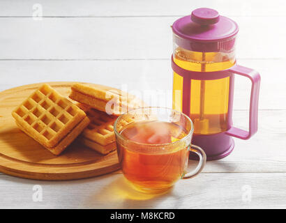 Selbstgemachte Waffeln mit Marmelade auf alten Holztisch. Wafer mit Tasse Kaffee und Teekanne. Stockfoto