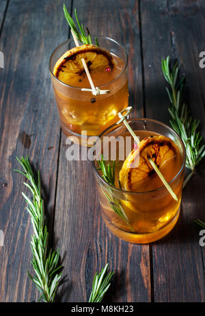 Alkohol Cocktail mit Zitrone, Eis und Rauchen Rosmarin auf dunklen Tisch. Stockfoto