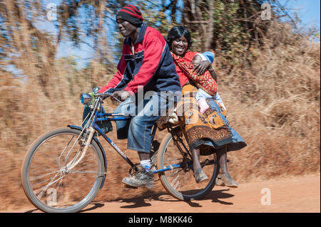 Menschen in Sambia, Afrika Reiten Fahrrad mit Frau und Kind auf dem Träger. Stockfoto