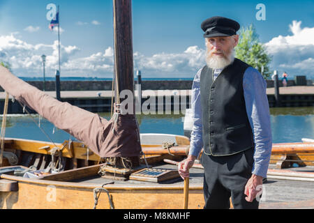 Alter Seemann steht für traditionellen Fischerboot im Hafen von Urk Stockfoto
