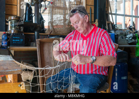 Mann in traditionellen niederländischen Kostüm ausbessern Fischernetze in Werkstatt Stockfoto