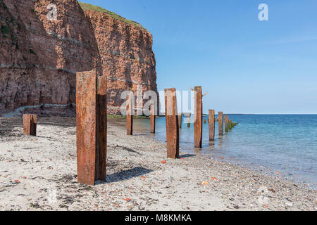 Strand Insel Helgoland mit roten Klippen und rostiges Eisen Säulen Stockfoto