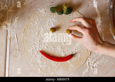 Teig für Pizza in der Form von Lächeln, auf den Tisch. Stockfoto