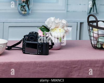 Ostern Korb mit bunten Eiern und Foto Kamera auf dem rosa Tabelle Stockfoto