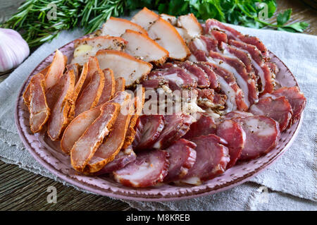 Große Fleisch gesetzt. Hausgemachte geräuchertes Schweinefleisch, Rindfleisch, Wurst, gesalzener Speck, basturma gehackt Schichten auf einem Holzbrett mit Gewürzen und Kräutern. Stockfoto