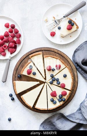 Classic New York Cheesecake mit frischen Himbeeren und Blaubeeren auf Weiß konkreten Hintergrund, Ansicht von oben Stockfoto