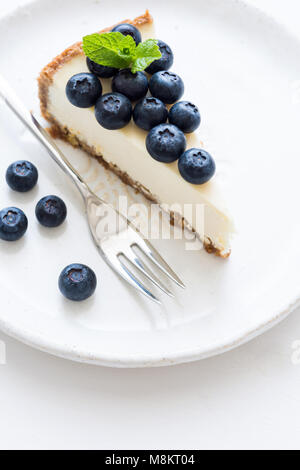 New York Cheesecake mit frischen Blaubeeren und Minze auf weißem Hintergrund, selektive konzentrieren. Blueberry Cheesecake Stockfoto