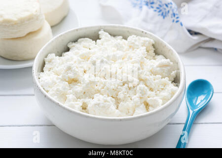 Tvorog, Landwirte Käse, Quark oder Hüttenkäse in Weiß Schüssel auf weiße Holztisch, Detailansicht. Reich an Calcium gesunde Ernährung Stockfoto