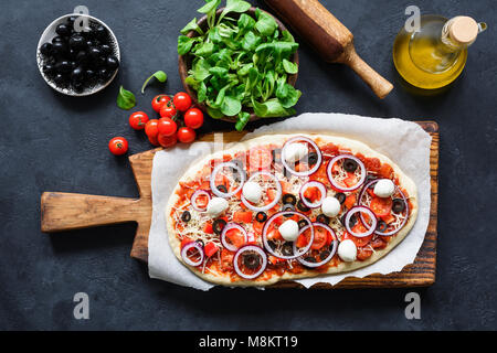 Hausgemachte Pizza Vorbereitung. Pizza Zutaten auf dunklem Hintergrund, Ansicht von oben Stockfoto