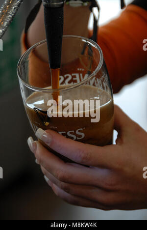 Ein Pint Guinness wird in ein Pint Glas in der Gravity Bar gegossen, wo Besucher sich im Guinness Storehouse in der Brauerei in Dublin in S entspannen Stockfoto