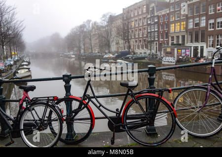 Dec 20, 2018 - Fahrrad angekettet an Geländer entlang eines Kanals in Amsterdam, Niederlande, auf einer nassen und nebligen Wintertag Stockfoto