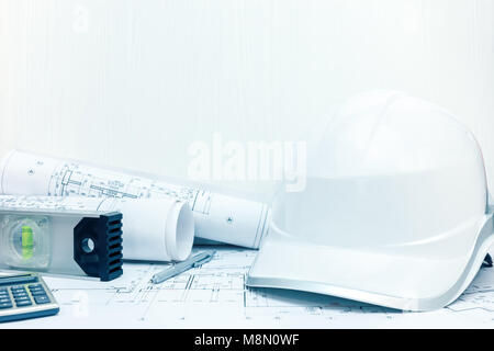Auftragnehmer Arbeitsplatz. Wasserwaage, Bleistift, Taschenrechner, Helm und blueprint Brötchen am Schreibtisch. Stockfoto