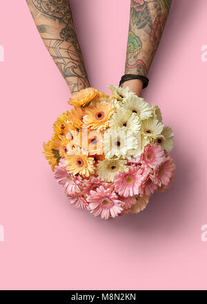 Schönen Blumenstrauß aus verschiedenen frischen Gerberas in die Hände eines Mädchens auf einem rosa Hintergrund Stockfoto