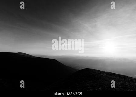 Kreuz auf dem Gipfel des Mt. Serrasanta (Umbrien, Italien), mit Sun niedrig am Horizont Stockfoto