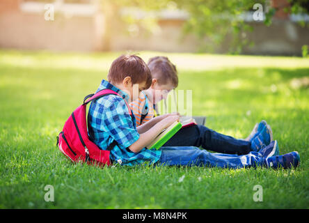 Kinder mit Rucksäcken stehen im Park in der Nähe von Schule Stockfoto