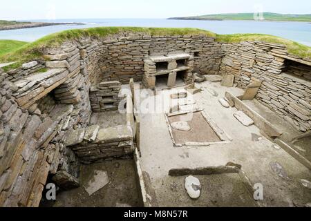 Skara Brae Steinzeit jungsteinzeitliche Dorf an Skaill, Orkney, Schottland. Interieur, Betten, Kamin und Kommode 3100 BC. Haus 1 mit Bucht von Skaill hinter Stockfoto