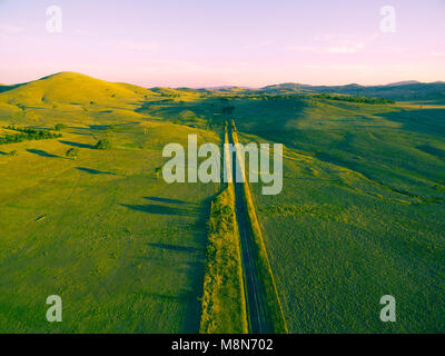 Gerade ländliche Straßen durch die Landschaft bei Sonnenuntergang Stockfoto