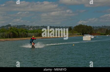 Bli Bli, QLD, Australien - März 17, 2018: Junge männliche Teenager reiten ein Wakeboard an einem Kabel Water park Stockfoto