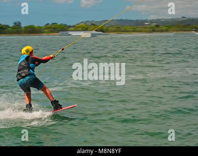 Bli Bli, QLD, Australien - März 17, 2018: Junge männliche Teenager reiten ein Wakeboard an einem Kabel Water park Stockfoto