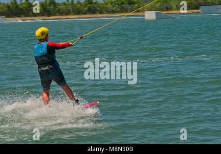 Bli Bli, QLD, Australien - März 17, 2018: Junge männliche Teenager reiten ein Wakeboard an einem Kabel Water park Stockfoto