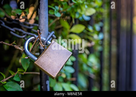 Metall Vorhängeschloss hängen an den schwarzen rostiges Metall Zaun Stockfoto