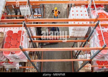Oben Ansicht Hintergrundbild von hohen Regal Zeilen in moderne Lagerhalle mit Arbeiter tragen, hardhat mittels Gabelstapler in Gang, kopieren Raum Stockfoto