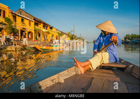 Vietnamesische Tourismusfarbe, Blick auf eine vietnamesische „Bootsfrau“ in einem konischen Hut, die auf dem Fluss Thu Bon in Hoi an, Zentralvietnam, gleitet. Stockfoto