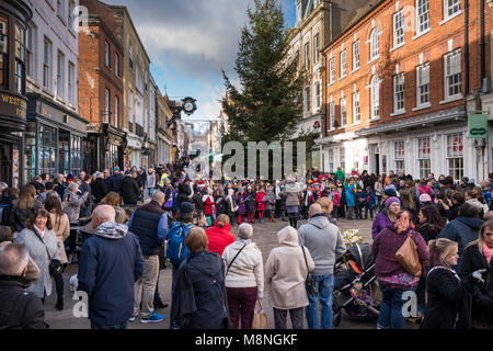 Junge Schule Kinder singen Weihnachtslied vor Weihnachten, High Street, Winchester, Hampshire, UK Stockfoto