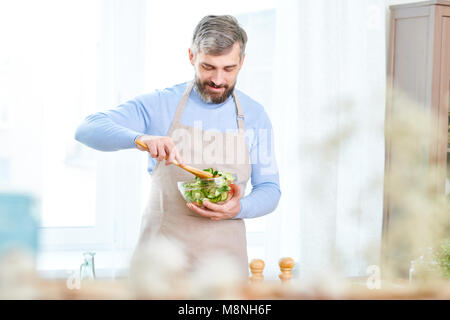 Gut aussehender bärtiger Mann, der Salat Stockfoto