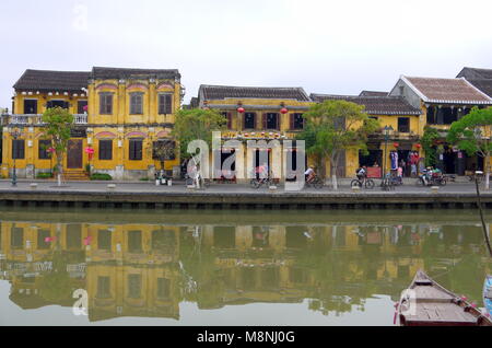 Hoi An, Vietnam - 17. MÄRZ 2018: Radfahren auf der Straße im Zentrum von Hoi An Vietnam mit Blick auf die typische gelbe Häuser am Ufer des Flusses Stockfoto