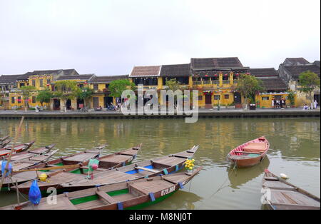 Hoi An, Vietnam - 17. MÄRZ 2018: Boote am Ufer des Flusses in der Altstadt Hoi An mit Blick auf die typische gelbe Häuser Stockfoto