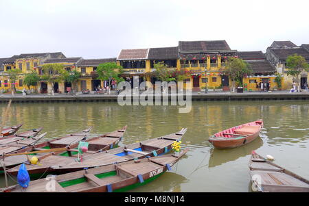 Hoi An, Vietnam - 17. MÄRZ 2018: Boote am Ufer des Flusses in der Altstadt Hoi An mit Blick auf die typische gelbe Häuser Stockfoto