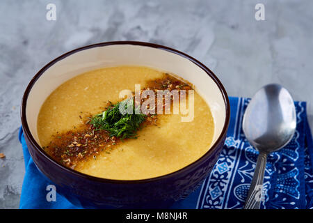 Lila porzellan Schale, cremige Kürbissuppe mit Dill garniert, serviert mit getoasteten Brotscheiben auf homespun Serviette über weiße strukturierte Hintergrund, Stockfoto