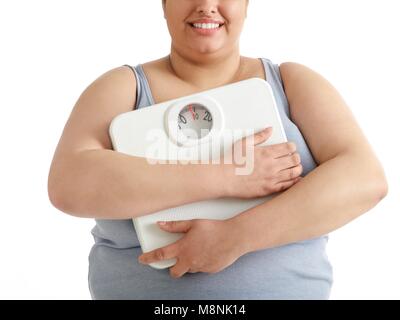 Übergewichtige Frau mit Waage, lächelnd. Stockfoto