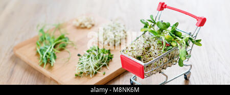 Micro Grüns in Warenkorb auf Holz- Hintergrund. Verschiedene Arten von microgreens zum Verkauf. Gesunde Ernährung Konzept der frischen Garten produzieren biologisch angebaut, Symbol der Gesundheit. Vitamine aus der Natur. Stockfoto