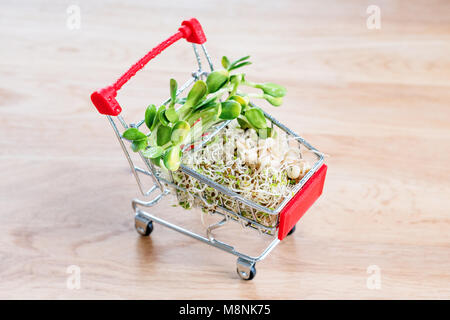 Micro Grüns in Warenkorb auf Holz- Hintergrund. Verschiedene Arten von microgreens zum Verkauf. Gesunde Ernährung Konzept der frischen Garten produzieren biologisch angebaut, Symbol der Gesundheit. Vitamine aus der Natur. Stockfoto