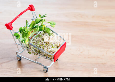 Micro Grüns in Warenkorb auf Holz- Hintergrund. Verschiedene Arten von microgreens zum Verkauf. Gesunde Ernährung Konzept der frischen Garten produzieren biologisch angebaut, Symbol der Gesundheit. Vitamine aus der Natur. Stockfoto