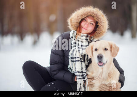 Bild der Frau in Schwarz Jacke hocken neben Hund in Winter Park Stockfoto