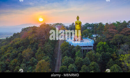 Luftaufnahmen der golden Big Buddha Statue stehend auf einem Hügel im Sonnenuntergang am Wat Phra That Jom Wae in Chiang Rai Thailand Stockfoto