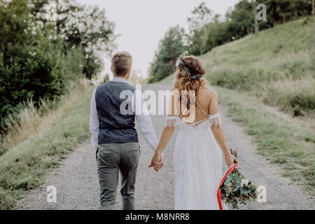 Schöne Braut und Bräutigam in der grünen Natur, halten sich an den Händen. Stockfoto