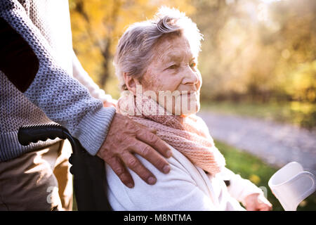 Älterer Mann und Frau im Rollstuhl im Herbst Natur. Stockfoto