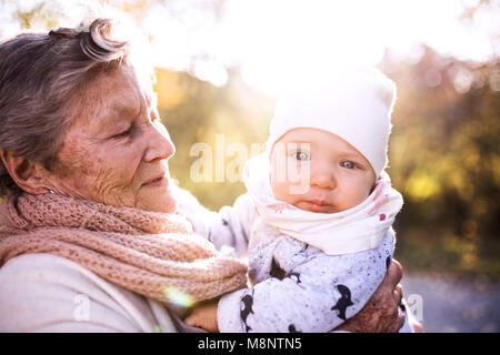 Eine ältere Frau mit einem Baby im Herbst Natur. Stockfoto