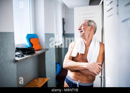 Älterer Mann durch die Schließfächer in ein Hallenbad. Stockfoto