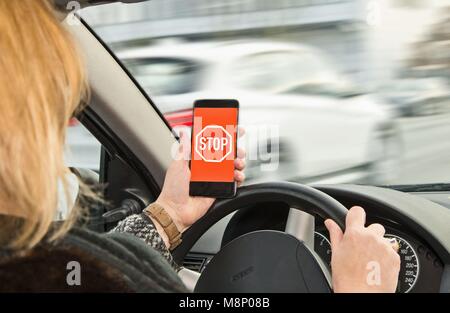 Frau hält ein Smartphone mit STOP-Schild in der Hand während der Fahrt | Verwendung weltweit Stockfoto